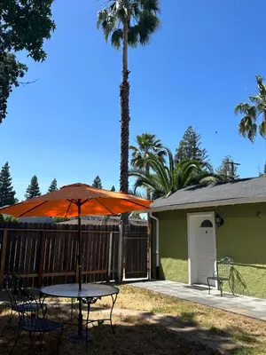 a table with an umbrella in front of a house at Private Suites in Sacramento