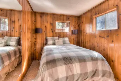 two beds in a room with wooden walls and windows at Badger Basin - 30 Days or more Vacation Home Rental in South Lake Tahoe