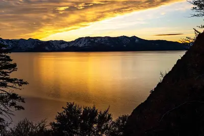a sunset over a large body of water with mountains at Badger Basin - 30 Days or more Vacation Home Rental in South Lake Tahoe