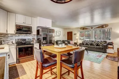 a kitchen and living room with a wooden table and chairs at Coziness Cabin - Cute little cabin in the Tahoe woods in South Lake Tahoe