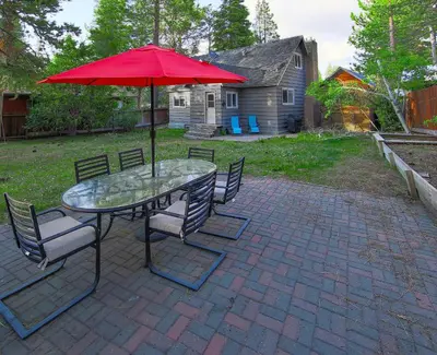 a table and chairs with a red umbrella on a patio at Dancing Bear Cabin - Pet Friendly Sleeps 4 Totally cute in South Lake Tahoe