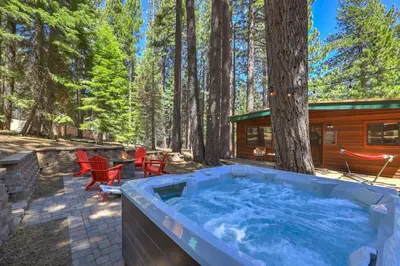a hot tub in the woods next to a cabin at Shady Pines Pets Hot tub in South Lake Tahoe