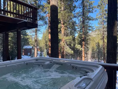 a jacuzzi tub in the snow in a forest at Nestled Pines Retreat Hot Tub Pool Tahoe Foosball More in South Lake Tahoe