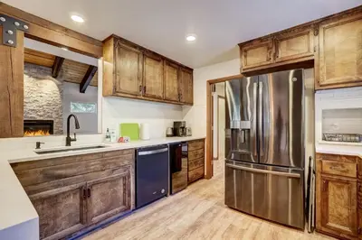 a kitchen with wooden cabinets and a stainless steel refrigerator at Singing Pines in Marla Bay - Walk to Lake in Glenbrook