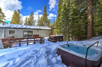 a hot tub in the snow in front of a house at Southern Pines Arcade Games & Foosball for Kids in South Lake Tahoe