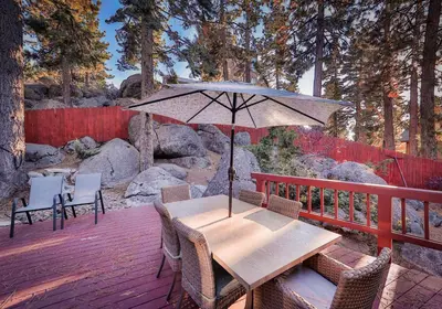a wooden table with an umbrella on a deck at Sunset Cove Chic Tahoe Retreat in Glenbrook