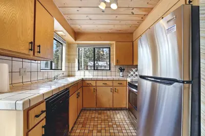 a kitchen with wooden cabinets and a stainless steel refrigerator at Tahoe Forest Chalet 3BR House with AC in Stateline