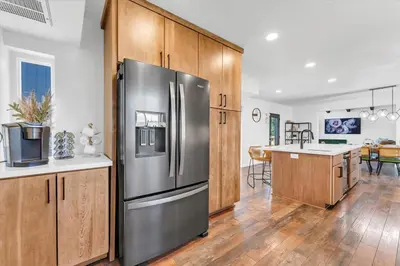 a kitchen with a stainless steel refrigerator and wooden cabinets at Family Retreat Mountain View with Hot Tub and Mini Golf in Steamboat