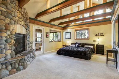 a bedroom with a large stone fireplace and a bed at Mountainside Overlook Lake Views & Hot Tub in Kings Beach