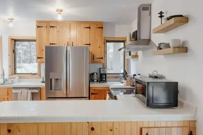 a kitchen with a stainless steel refrigerator and wooden cabinets at North Lake Hideaway Prime Locale for Outdoor Fun in Alpine Meadows