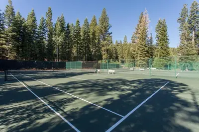 a tennis court with trees in the background at Luxury Northstar Palace with Hot Tub & Games in Truckee