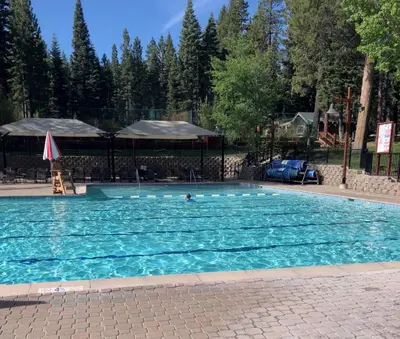 a large swimming pool with a person in the water at Northstar Treehouse Chic 4BR House Forest view in Truckee