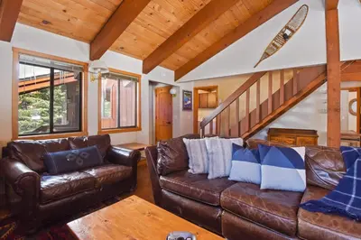 a living room with leather couches and a staircase at Northstar Treehouse Chic 4BR House Forest view in Truckee