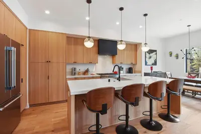 a kitchen with wooden cabinets and a large island with bar stools at Enjoy Paradise Hot Tub Bike & Beach Equipment in Olympic Valley