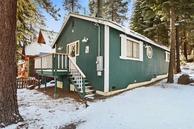 a green house with a staircase in the snow at Pino Point Steps to Tahoe Beaches in Tahoe Vista