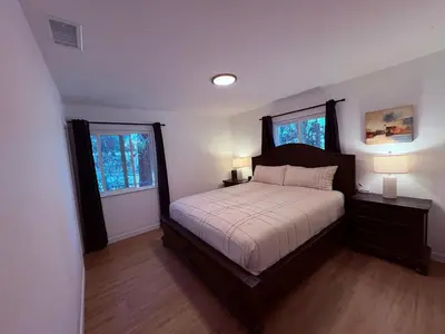 a bedroom with a large bed and two windows at Downtown-Pool,Firepit,Trees, WFH-No gate fee like PML in Groveland