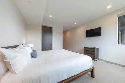 a bedroom with a white bed and a television at Village Walk 7470 by East West Hospitality in Truckee