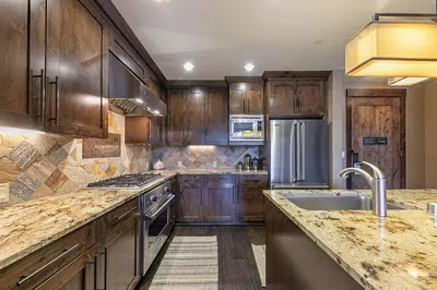 a kitchen with wooden cabinets and a stainless steel refrigerator at Northstar Lodge 306 by East West Hospitality in Truckee