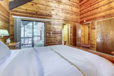 a bedroom with a bed in a room with wooden walls at Resting Bear Lodge by Tahoe Getaways - Pet Friendly w Foosball and HOA Amenities in Truckee