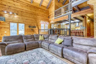 a large brown couch in a room with wooden walls at Resting Bear Lodge by Tahoe Getaways - Pet Friendly w Foosball and HOA Amenities in Truckee