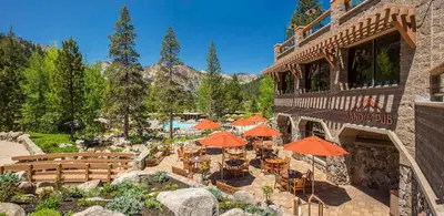 a restaurant with tables and umbrellas in front of a building at Everline Resort & Spa Palisades-Valley View Suite in Olympic Valley