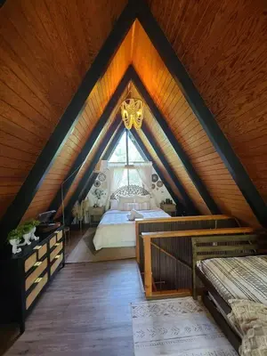 a attic bedroom with a bed and a window at Sequoia A-frame Nirvana: Modern + Views + Hot Tub in Ponderosa