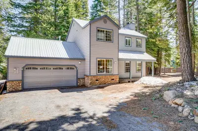 a white house with a garage in the woods at Truckee Retreat half Mi to Tahoe Donner Skiing in Truckee