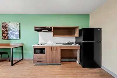 a kitchen with a black refrigerator and a table at ECHO Suites Extended Stay by Wyndham Reno in Reno