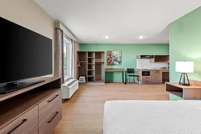 a bedroom with a flat screen tv and a living room at ECHO Suites Extended Stay by Wyndham Reno in Reno