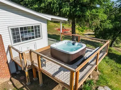 a hot tub on a deck next to a house at Yosemite Family Ranch in Oakhurst