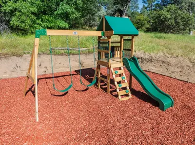 a small playground with a slide and a swing at Yosemite Family Ranch in Oakhurst