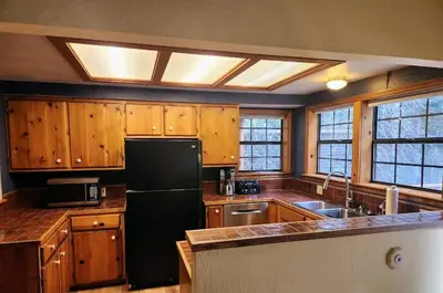 a kitchen with wooden cabinets and a black refrigerator at Relax Inn - Close to Attractions Galore in Truckee