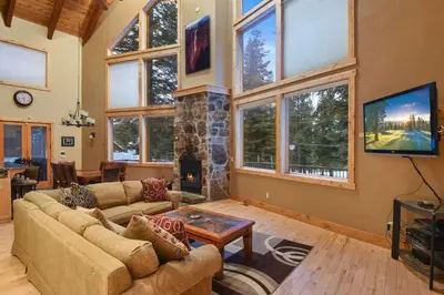 a living room with a couch and a stone fireplace at Skislope Sanctuary - Close to Outdoor Activities in Truckee