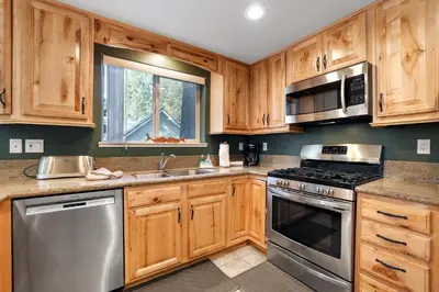 a kitchen with wooden cabinets and stainless steel appliances at Tahoe Frost - Air conditioned 4 bedroom Tahoe home in South Lake Tahoe