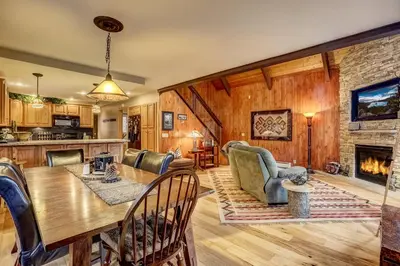 a kitchen and living room with a table and a fireplace at Woodland Escape - Cute Little Cabin in the Woods in South Lake Tahoe
