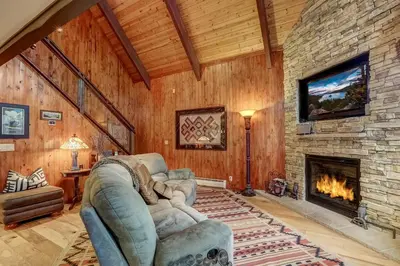 a living room with a large stone fireplace at Woodland Escape - Cute Little Cabin in the Woods in South Lake Tahoe