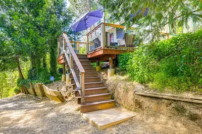 a house with a staircase and an umbrella at Peaceful Forest Views and Patio Twain Harte Home in Twain Harte