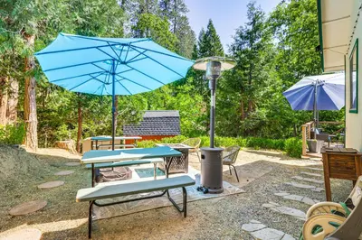 a table and chairs with a blue umbrella at Peaceful Forest Views and Patio Twain Harte Home in Twain Harte