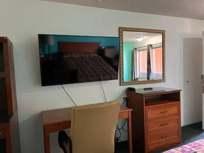 a bedroom with a bed and a desk and a mirror at Oasis Inn and Suites in Fallon