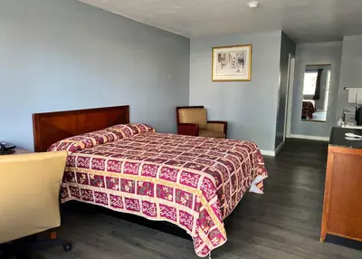 a bedroom with a bed with a red and white blanket at Oasis Inn and Suites in Fallon