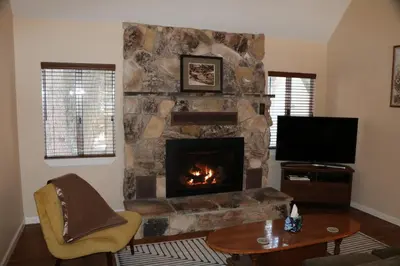 a living room with a stone fireplace with a television at Bear Meadow Cabin at Shaver Lake in Shaver Lake