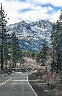 an empty road in front of a snow covered mountain at RR-Hideaway_Down_Cyn 104 in June Lake