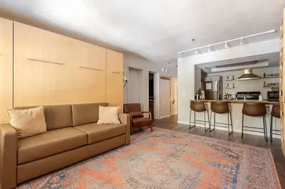 a living room with a couch and a kitchen at Super-Efficient Studio with Full Kitchen Balcony & Smart Sleeping Options in Kirkwood