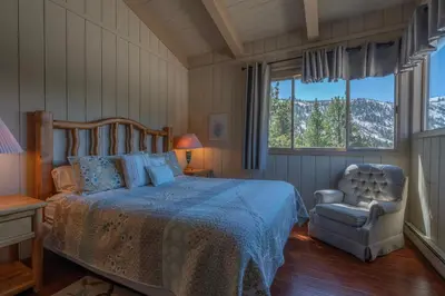 a bedroom with a bed and a chair and windows at RR-Villa Lago STR AP 18-003 in June Lake