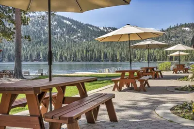 a group of picnic tables with umbrellas and a lake at 212 Bldg B condo in Truckee