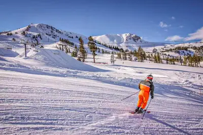 a person is skiing down a snow covered slope at Mammoth Point 119 in Mammoth Lakes