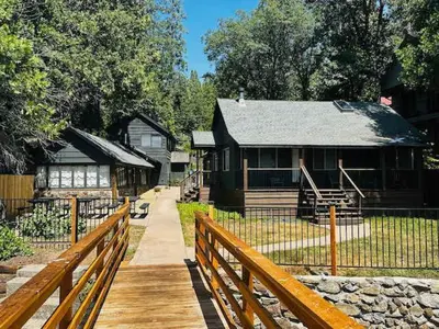 a wooden walkway leading to a house with a fence at Lewis Cabin - Boat Dock - Lake Front - Sleeps 10 in Bass Lake