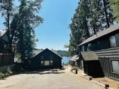 a house and a barn with a lake in the background at Lewis Cabin - Boat Dock - Lake Front - Sleeps 10 in Bass Lake