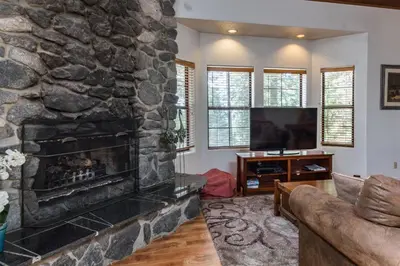 a living room with a stone fireplace and a television at Inside Yosemite Mountain Beauty in Yosemite West