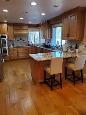a kitchen with wooden cabinets and a large island with chairs at Grass Valley Oasis - Spacious Family Retreat Near Rollins Lake in Grass Valley